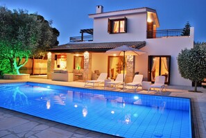 A modern two-story house with a swimming pool, outdoor seating, and a well-lit patio area. - 3 bedroom Villa Pera 12 with 10x5m private pool, within walking distance to resort village square, resort facilities, Aphrodite Hills (Kouklia)