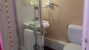 A bathroom with a glass shower enclosure, a sink, a mirror, a hairdryer, and a toilet. - Hotel le Vendangerot (Rully)