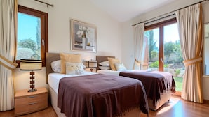 Quarto com duas camas, mesa de cabeceira, abajur e um quadro na parede.