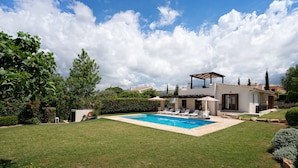 Uma casa moderna com piscina, alpendre coberto e um jardim bem cuidado.