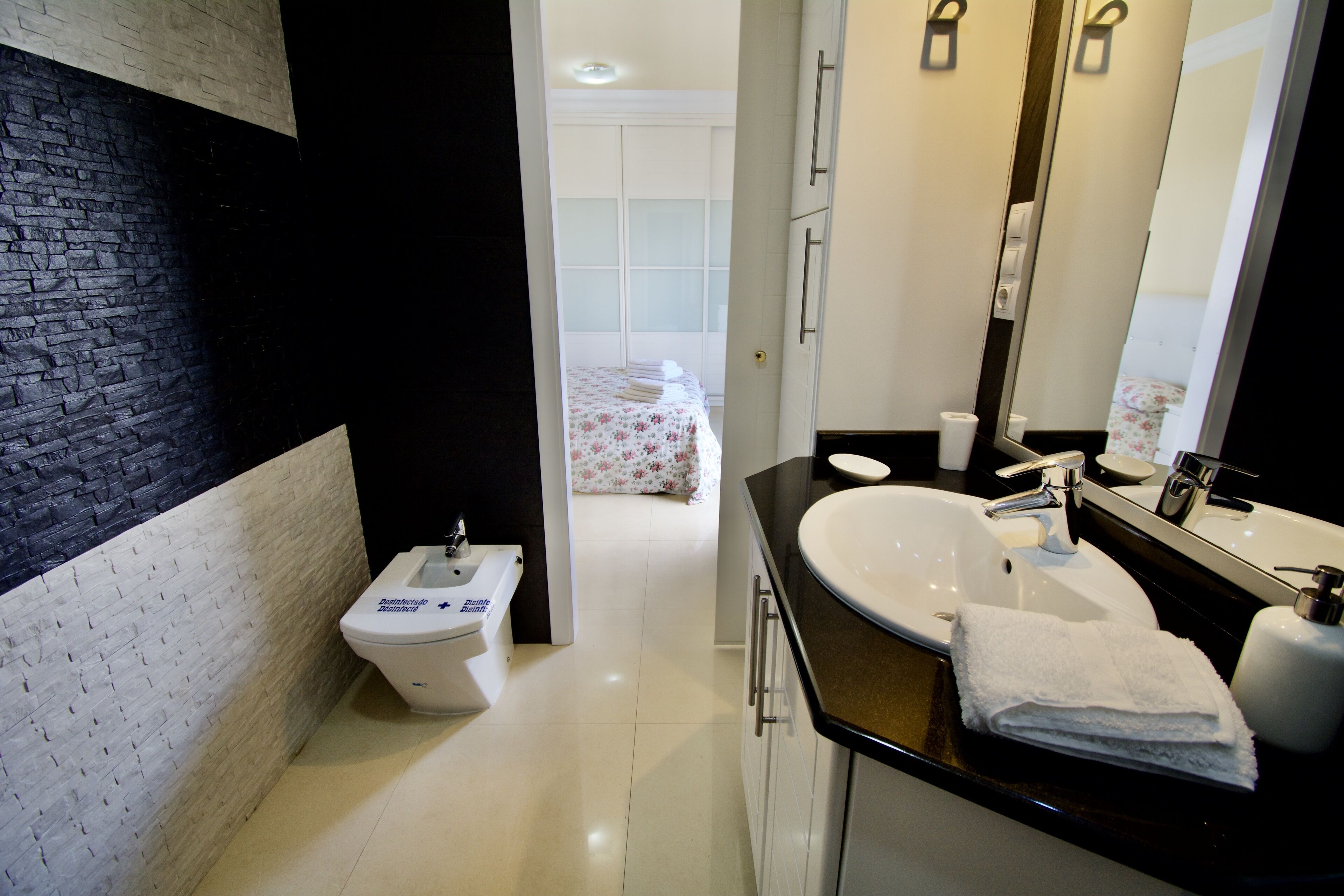 A modern bathroom with a toilet, sink, and mirror.