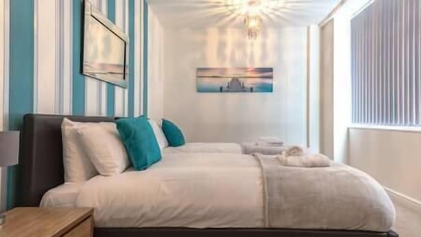 Une chambre à coucher avec un lit, des tables de chevet, une commode et un tableau au mur.