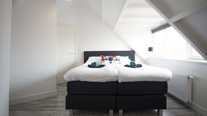 Een moderne slaapkamer met een groot dakraam, een bed met witte beddengoed en een zwart hoofdeinde.