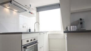 Een moderne keuken met witte kastjes, een inbouwoven, een spoelbak en een raam met uitzicht.