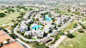 A residential area with modern white buildings, a central swimming pool, and surrounding green spaces. - Apartment DC01 - Kalypso (Kouklia)