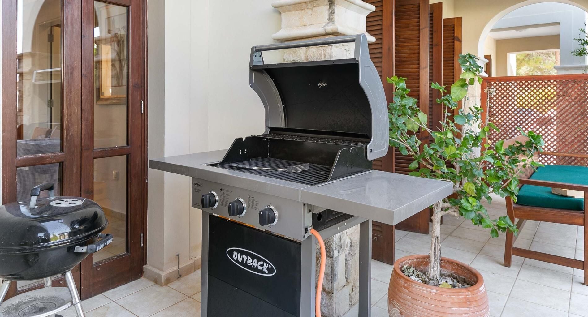 An outdoor grill with a chimney, a side burner, and a built-in thermometer.