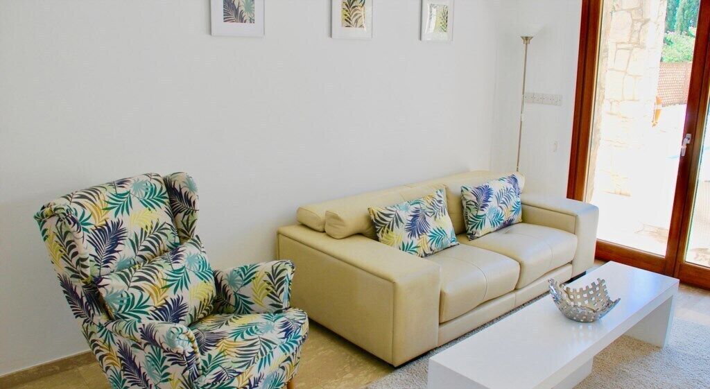 A living room with a beige sofa, a floral armchair, and a white coffee table.