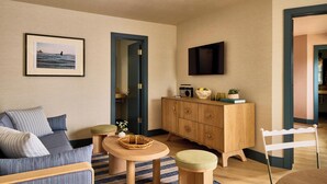 A living room with a sofa, a wooden cabinet, a television, and a framed picture on the wall.