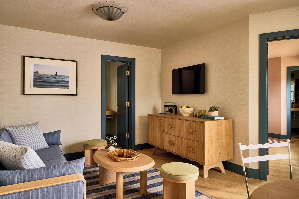 Een woonkamer met een bank, een houten kast, een televisie en een ingelijst kunstwerk aan de muur.