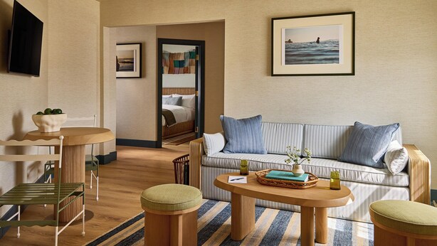A hotel room with a sofa, a coffee table, a TV, and a framed picture on the wall.