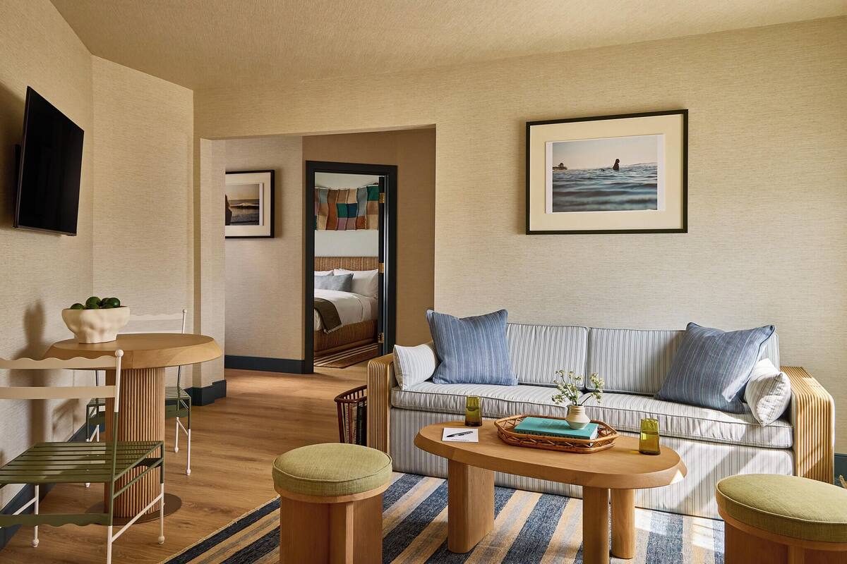 Een hotelkamer met een bank, een bijzettafeltje, een televisie en een ingelijste foto aan de muur.