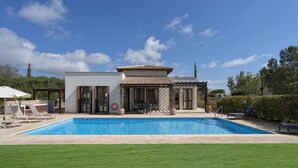 Ein modernes Haus mit Schwimmbad, einer Pergola und einer überdachten Terrasse.