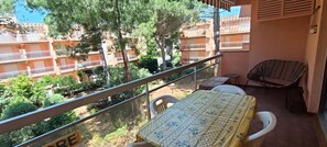 A balcony with a table and chairs, overlooking a residential area with trees and buildings.