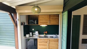 Cocina compacta con armarios de madera, un microondas, una cafetera y un lavabo.
