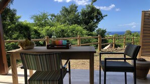 Un área de estar al aire libre con una mesa, sillas, un cuenco de fruta y una bandeja con vasos de colores.