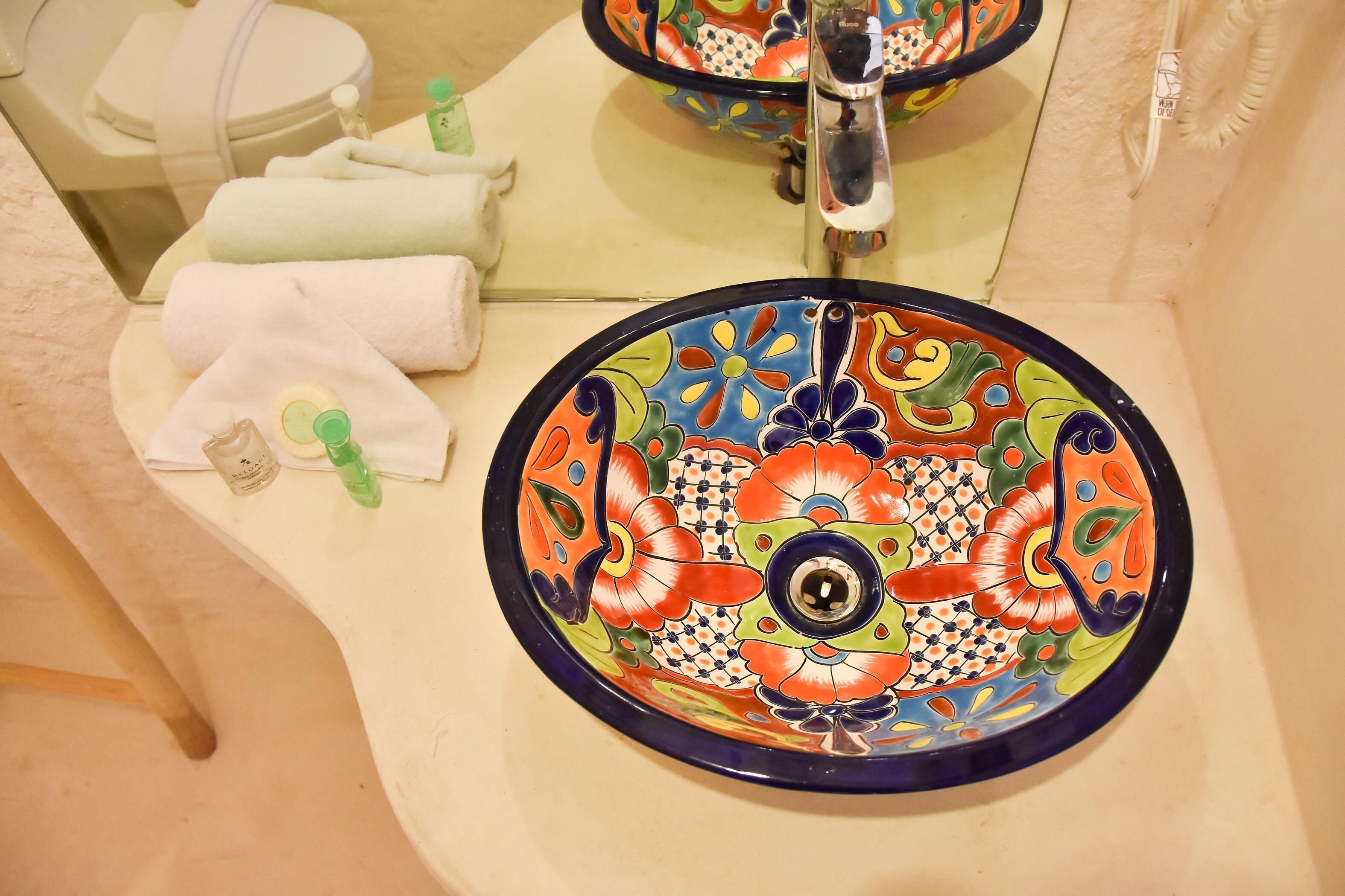 A bathroom sink with a colorful ceramic basin and a mirror above it.