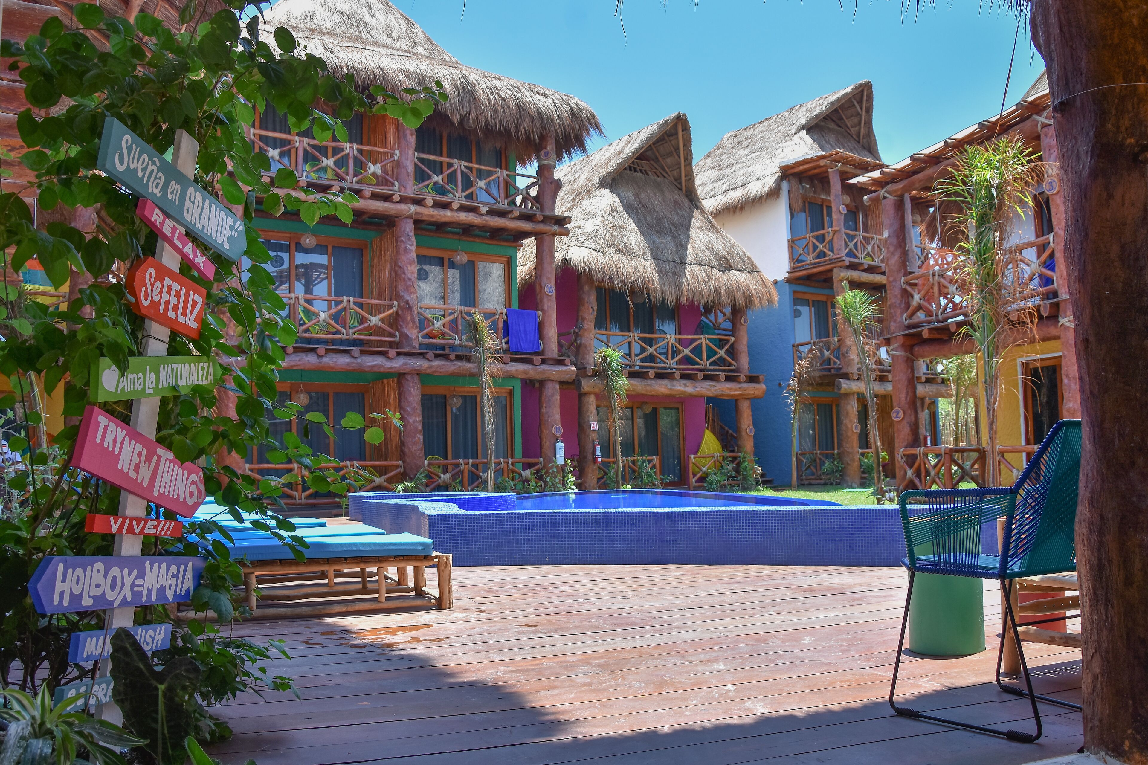 Un complexe hôtelier doté d’une piscine, d’une terrasse en bois et de bâtiments à toits de chaume.