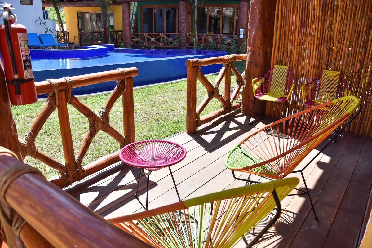 A wooden deck with colorful chairs and a blue pool.