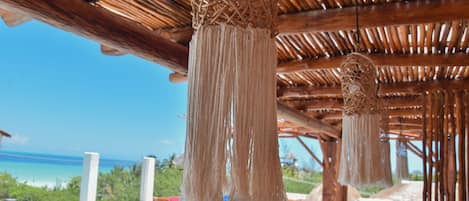 A beachside pool area with a wooden ceiling and hanging macramé decorations.