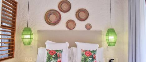 A bedroom with a bed, two nightstands, a wall-mounted lamp, and a window with wooden blinds.