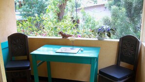 A small patio with a turquoise table and two chairs, a bird perched on the window sill, and a potted plant. - Luxury Studio in Secure Atitlan Complex (Panajachel)