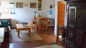 A cozy living room with a wooden table, a sofa, and a TV mounted on the wall. - Luxury Studio in Secure Atitlan Complex (Panajachel)