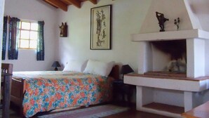 A bedroom with a bed, a fireplace, a window with curtains, and a framed picture on the wall. - Luxury Studio in Secure Atitlan Complex (Panajachel)
