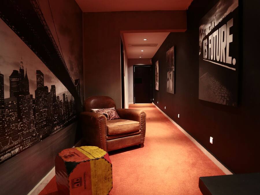 A hallway with a cityscape mural, a leather armchair, and a red carpet.