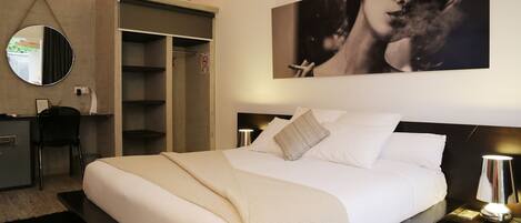 A modern bedroom with a large bed, a wardrobe, a desk, and a mirror.