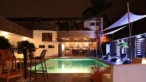 A pool area with lounge chairs, a bar, and a seating area with chairs and tables. - Le Stanislas Maison d'Hôtes (Abidjan)