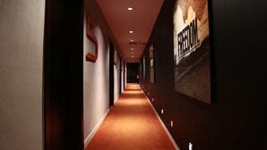 A long, narrow hallway with a red carpet, walls adorned with framed pictures, and a large 'FREEDOM' sign on the right. - Le Stanislas Maison d'Hôtes (Abidjan)