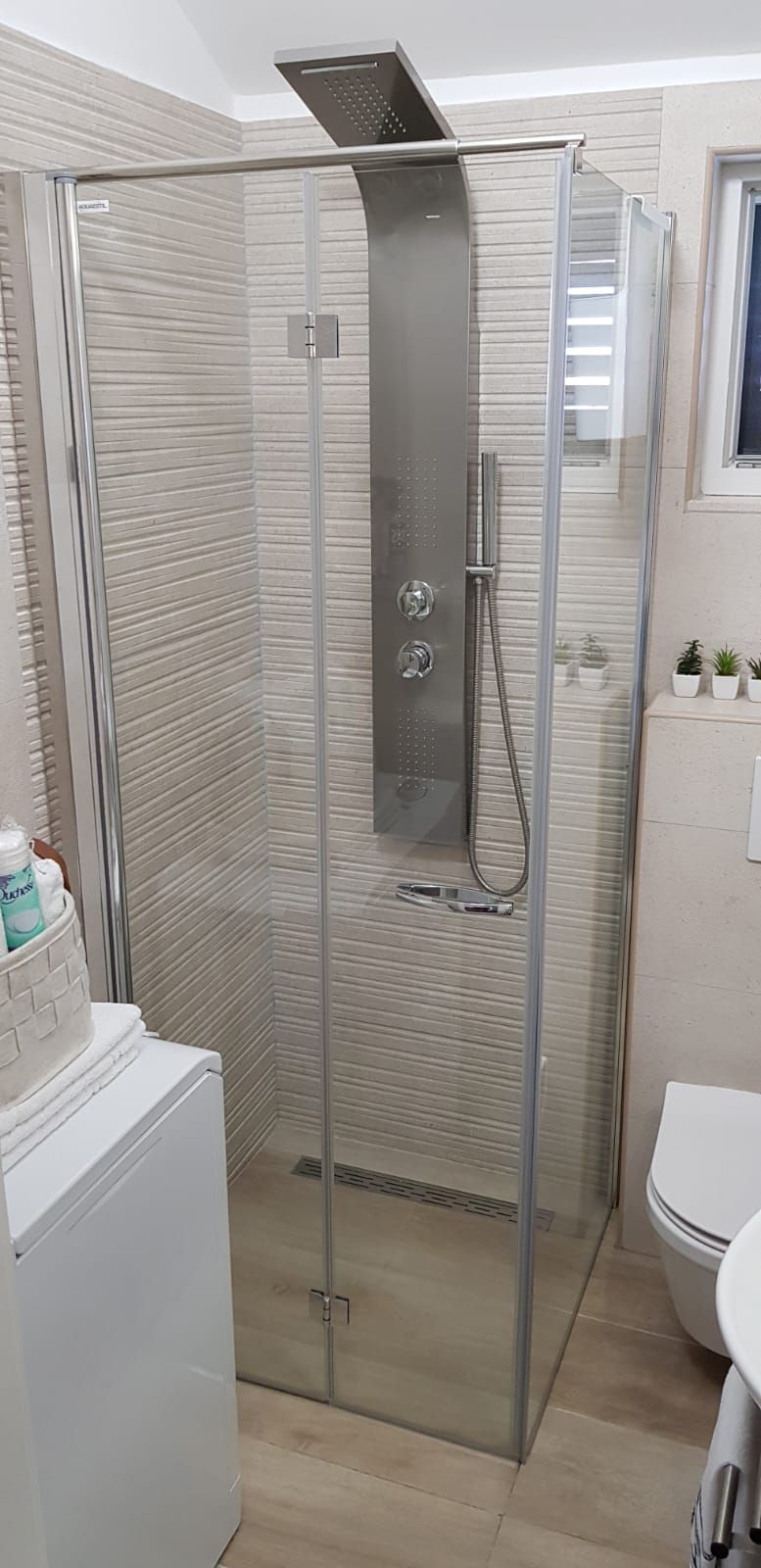 A glass-enclosed shower stall with a handheld showerhead and a wall-mounted faucet.