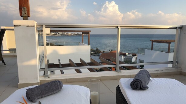 A balcony with two beds, a view of the sea, and a building named "Aqua Sol" in the background. - Marina Thea Villa No. 11 (Coral Bay)