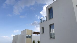 A modern building with multiple balconies and windows, overlooking a body of water. - Marina Thea Villa No. 11 (Coral Bay)