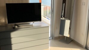 A bedroom with a bed, a TV on a dresser, a large mirror, and a view of the sea. - Marina Thea Villa No. 11 (Coral Bay)