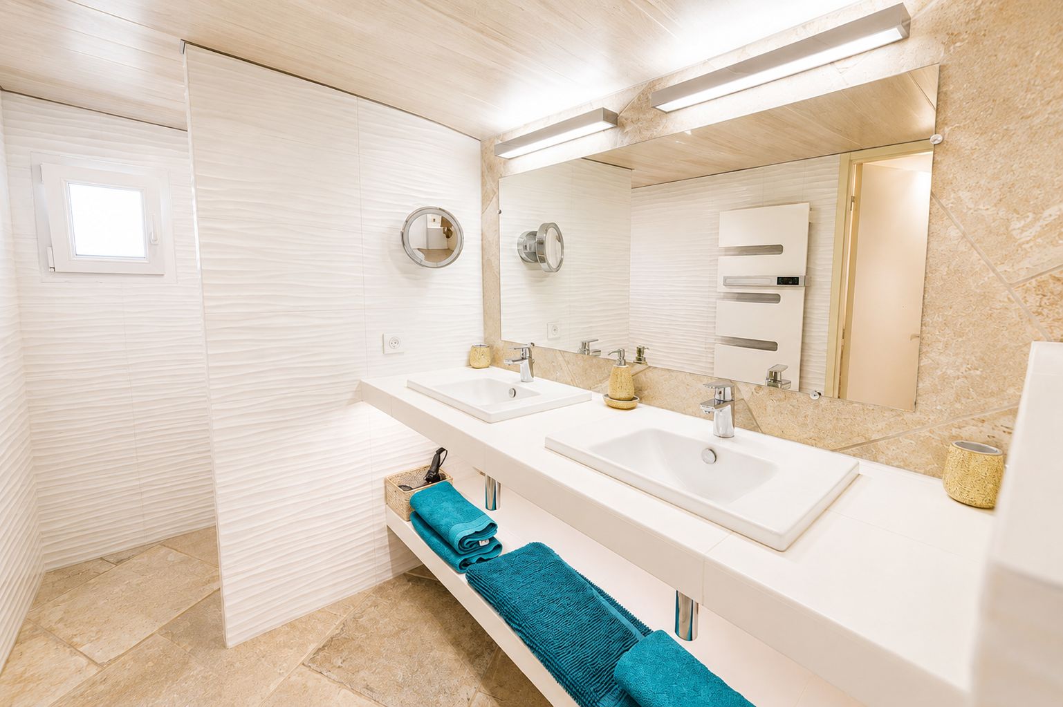 A modern bathroom with two sinks, a large mirror, and a towel rack.