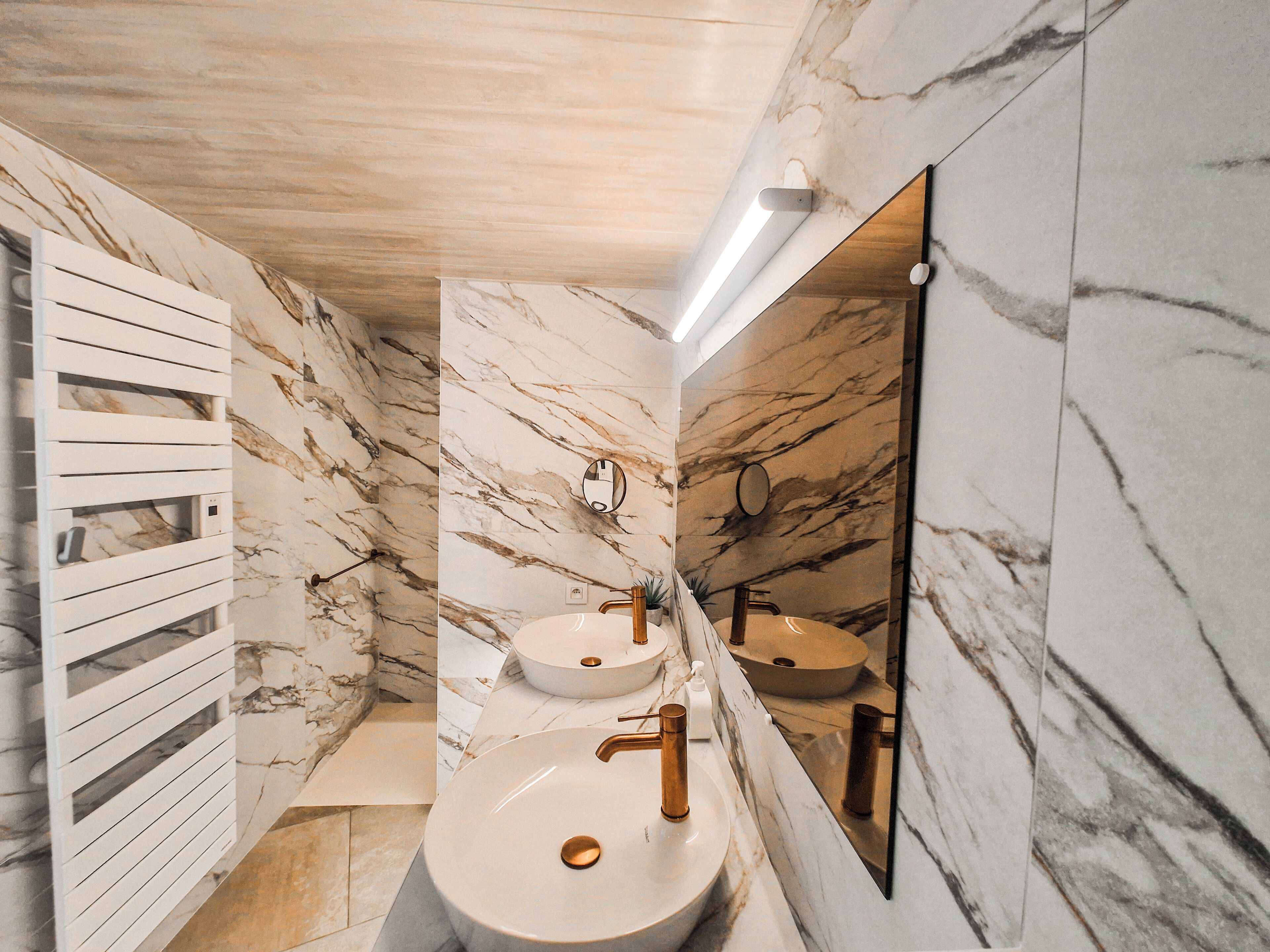 Un bagno con pareti in marmo, due lavabi e uno specchio.