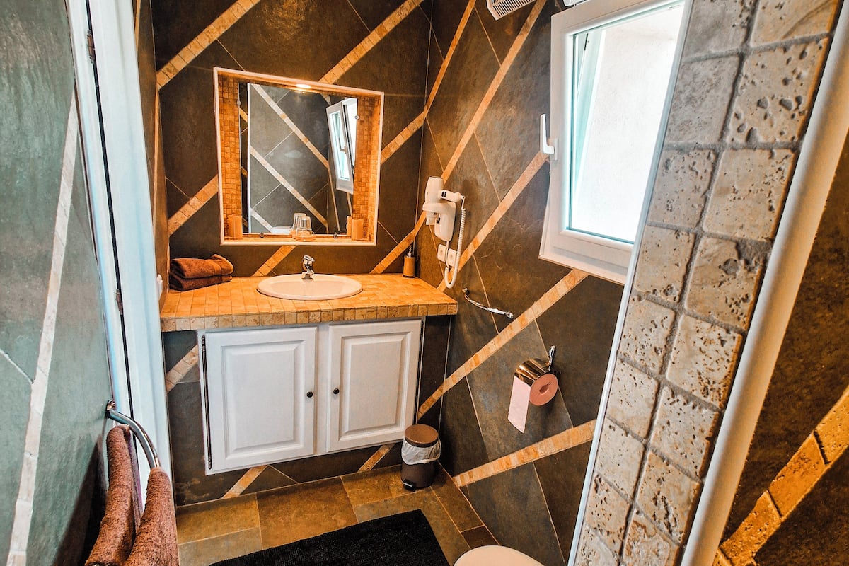 Een badkamer met een wastafel, spiegel, toilet en douche.