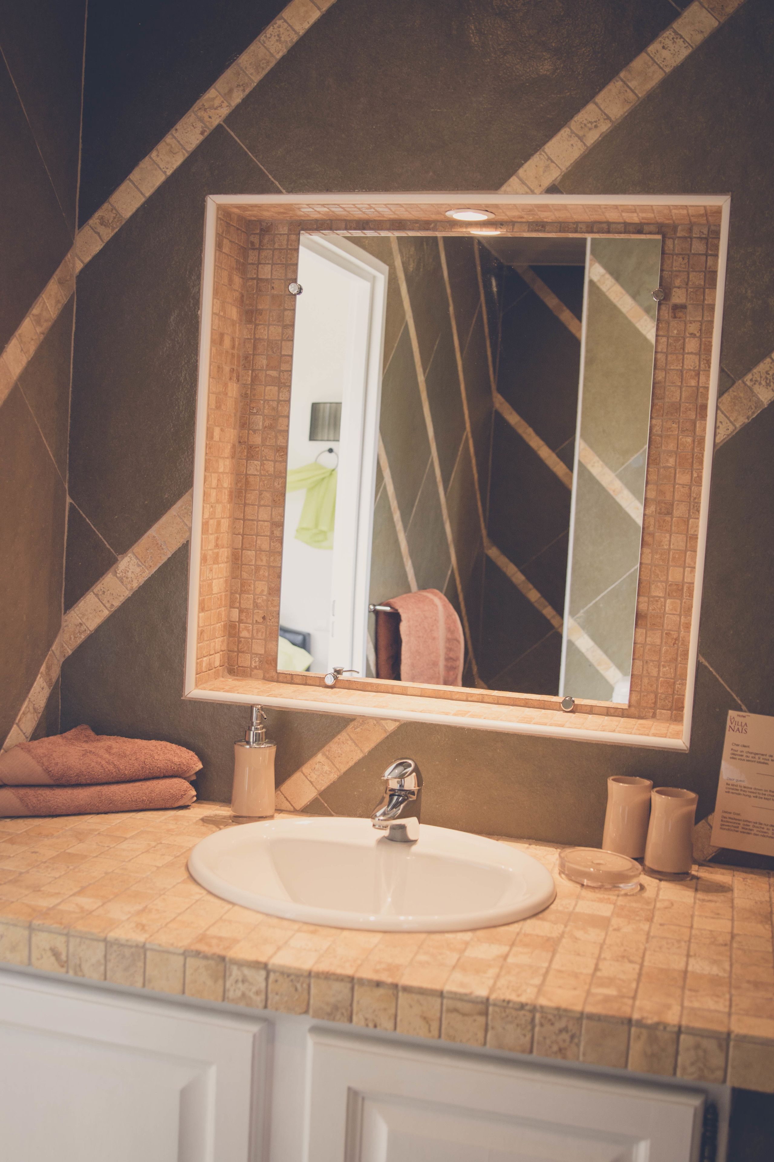 Une salle de bain avec un grand miroir, un lavabo et un porte-serviettes.