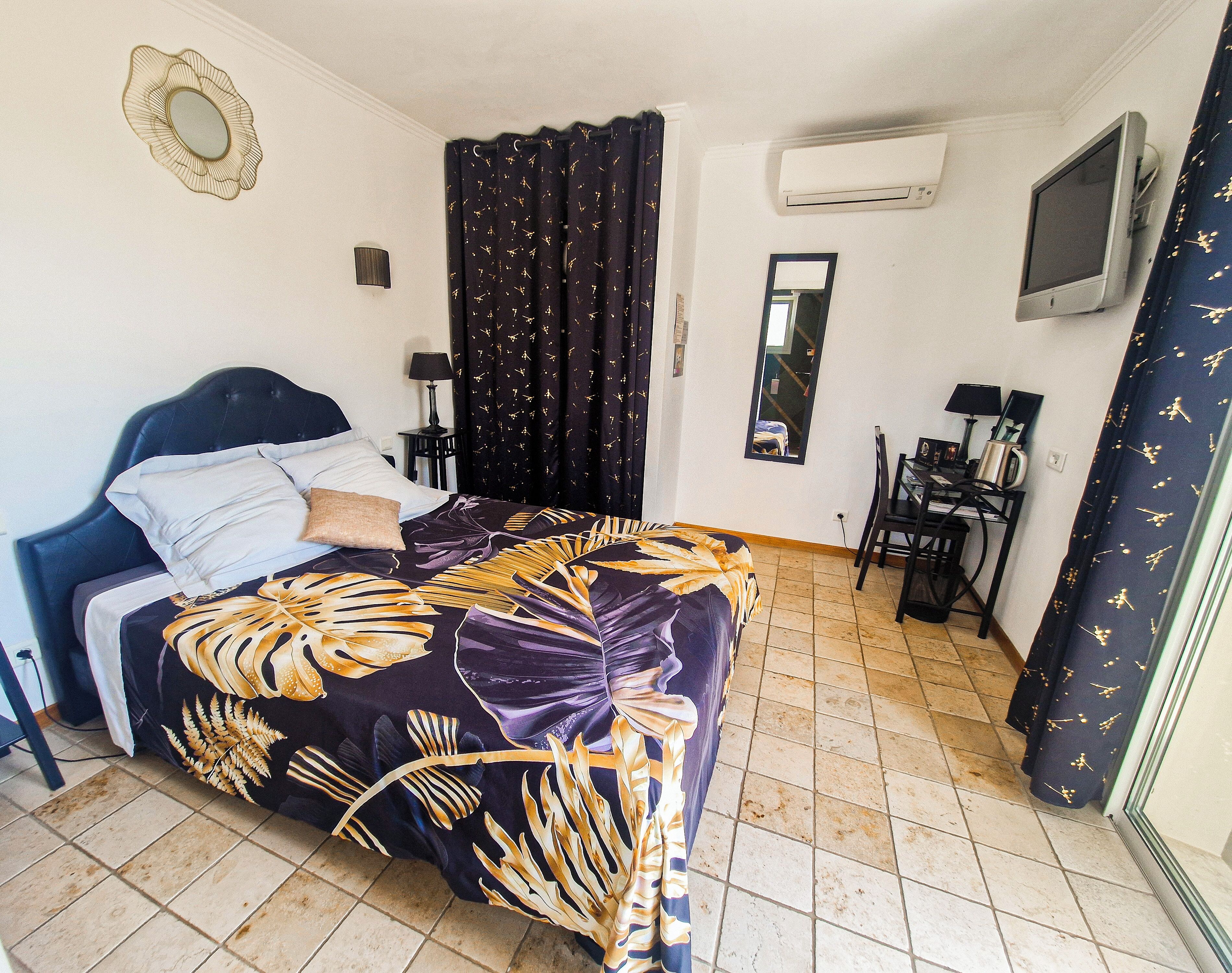Un dormitorio con cama, escritorio, silla, espejo y aire acondicionado.