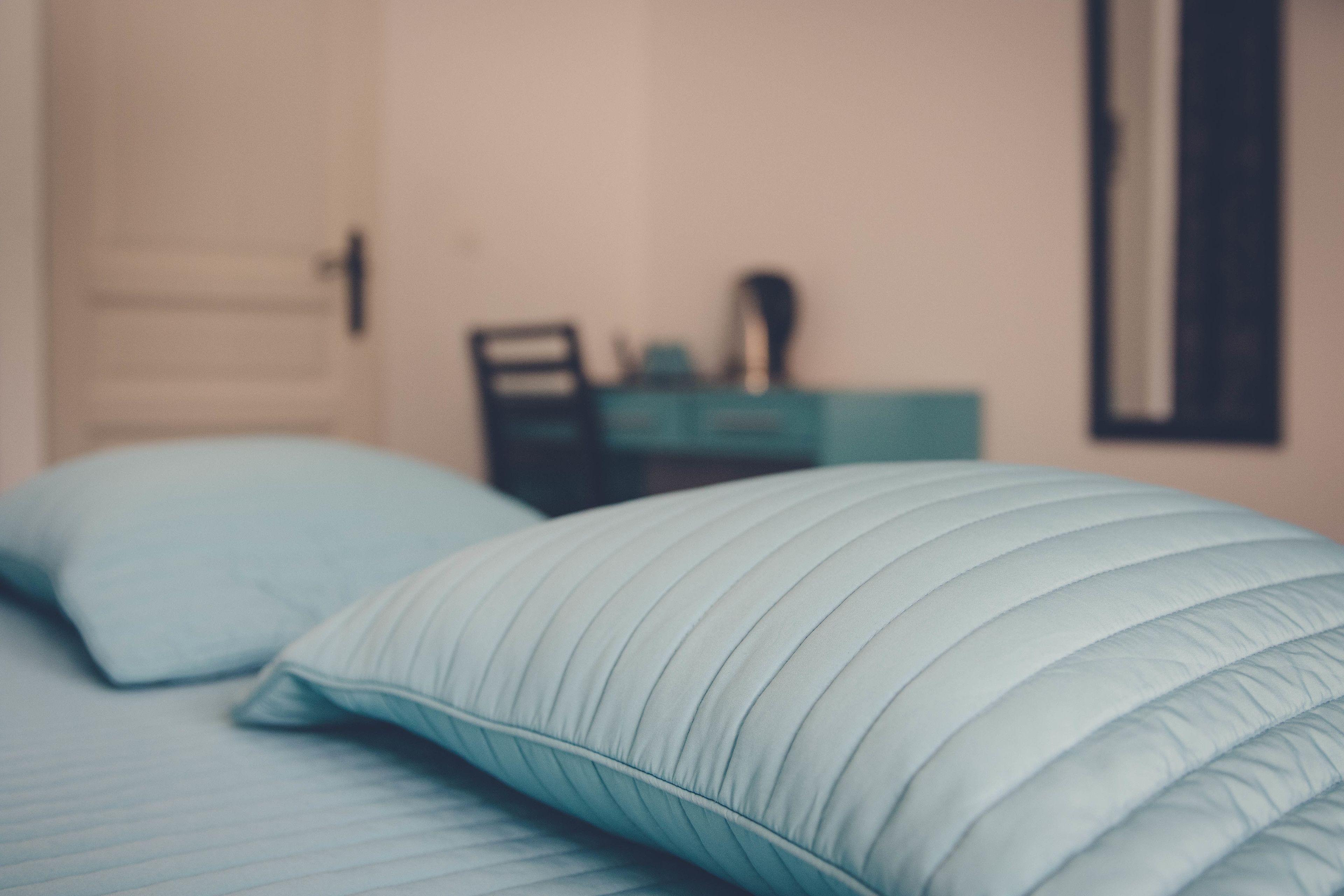 A bedroom with a bed, pillows, a dresser, and a mirror.