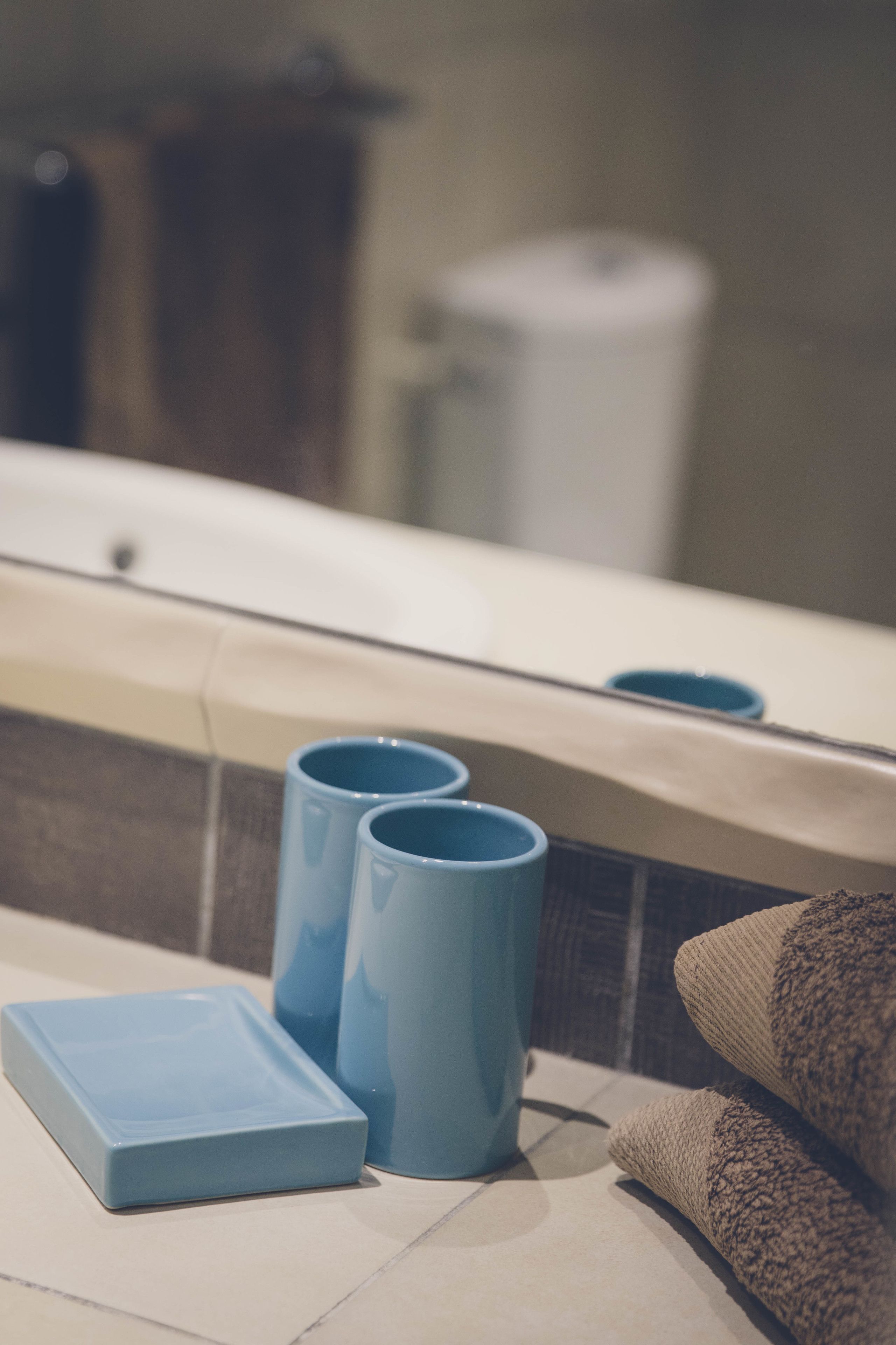 Un baño con una bañera, dos tazas azules y una toalla en el suelo.
