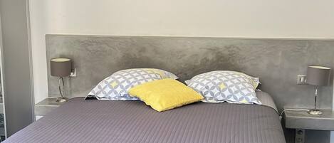 A bedroom with a bed, a wall-mounted air conditioner, and a ceiling light fixture.