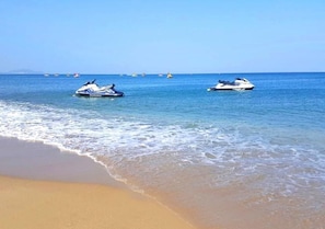 A beach with two jet skis on the water and a sandy shore.