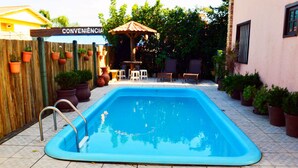 Une piscine entourée d’une clôture en bois et agrémentée de plantes en pot.