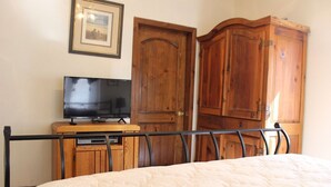 A bedroom with a bed, a television on a wooden cabinet, and wooden wardrobes.