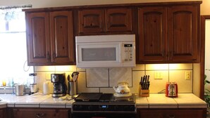 A kitchen with wooden cabinets, a microwave, a stove, and various kitchen appliances.