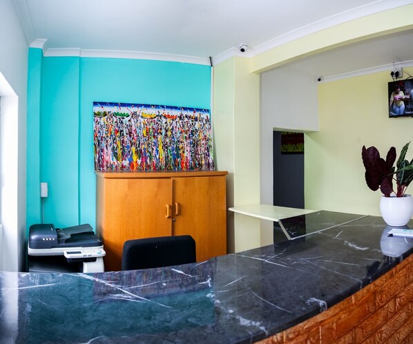 A modern kitchen with a marble countertop, a wooden cabinet, and a colorful painting on the wall. - Annex Lodge (Cape Town)