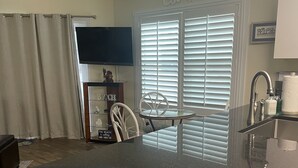A kitchen with a granite countertop, white cabinets, a built-in oven, and a window with blinds.