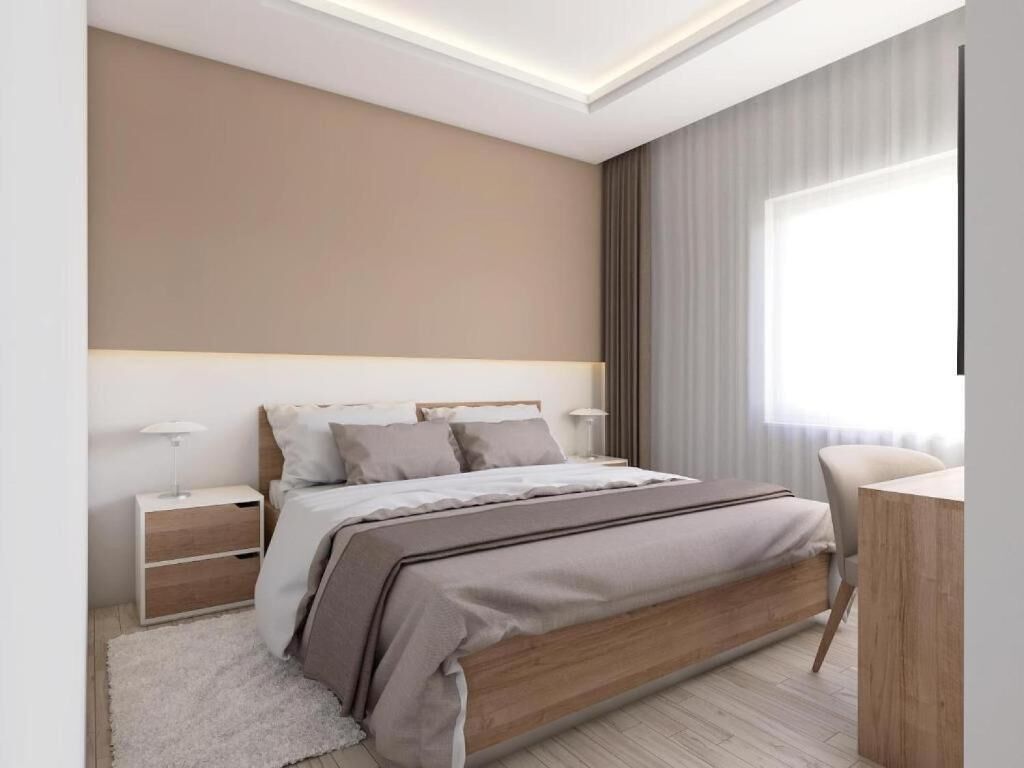 A modern bedroom with a large bed, bedside tables, a desk, and a window with curtains.